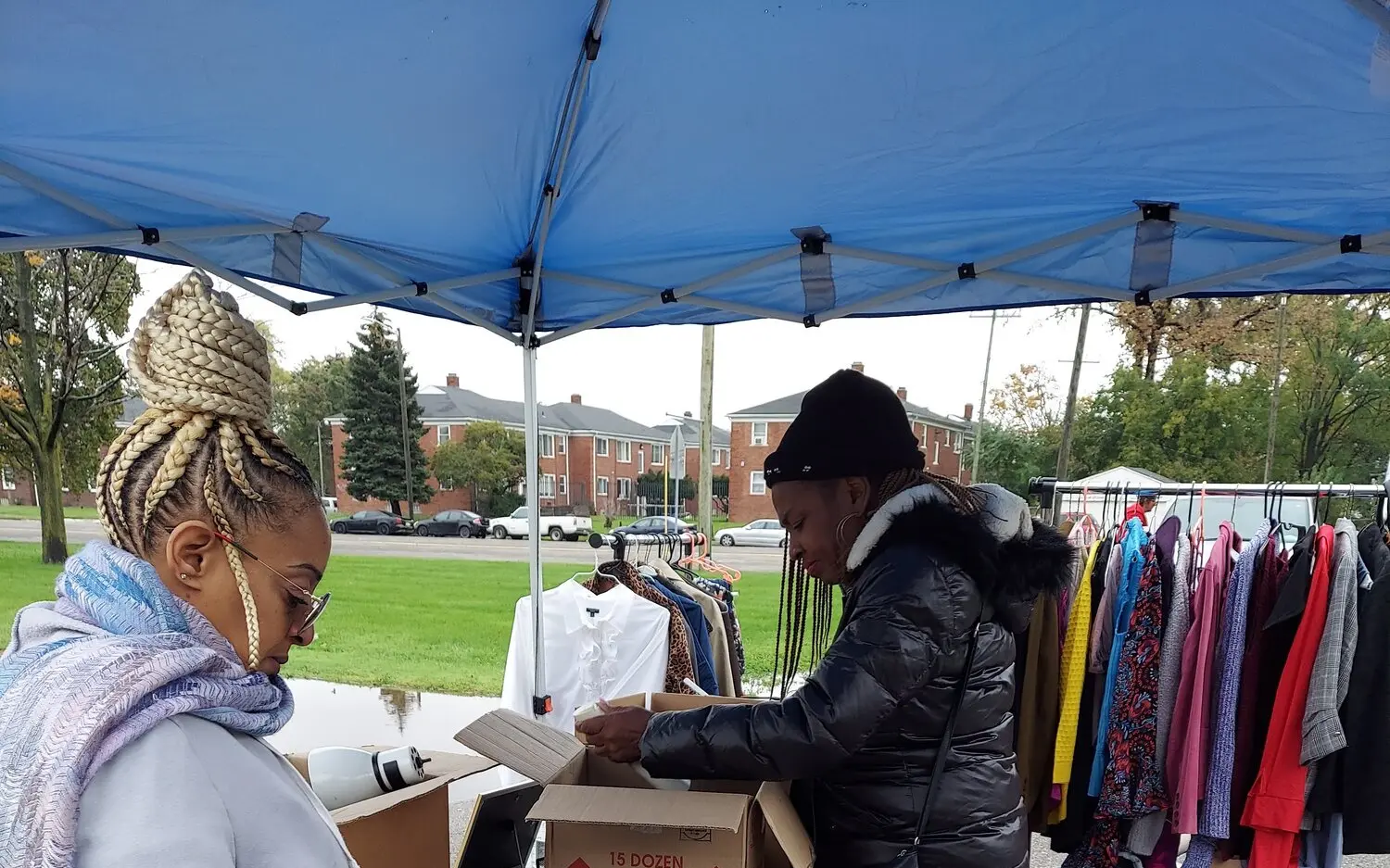 Community members sorting donated clothing under a blue tent at a L.I.V.E. Outreach distribution event