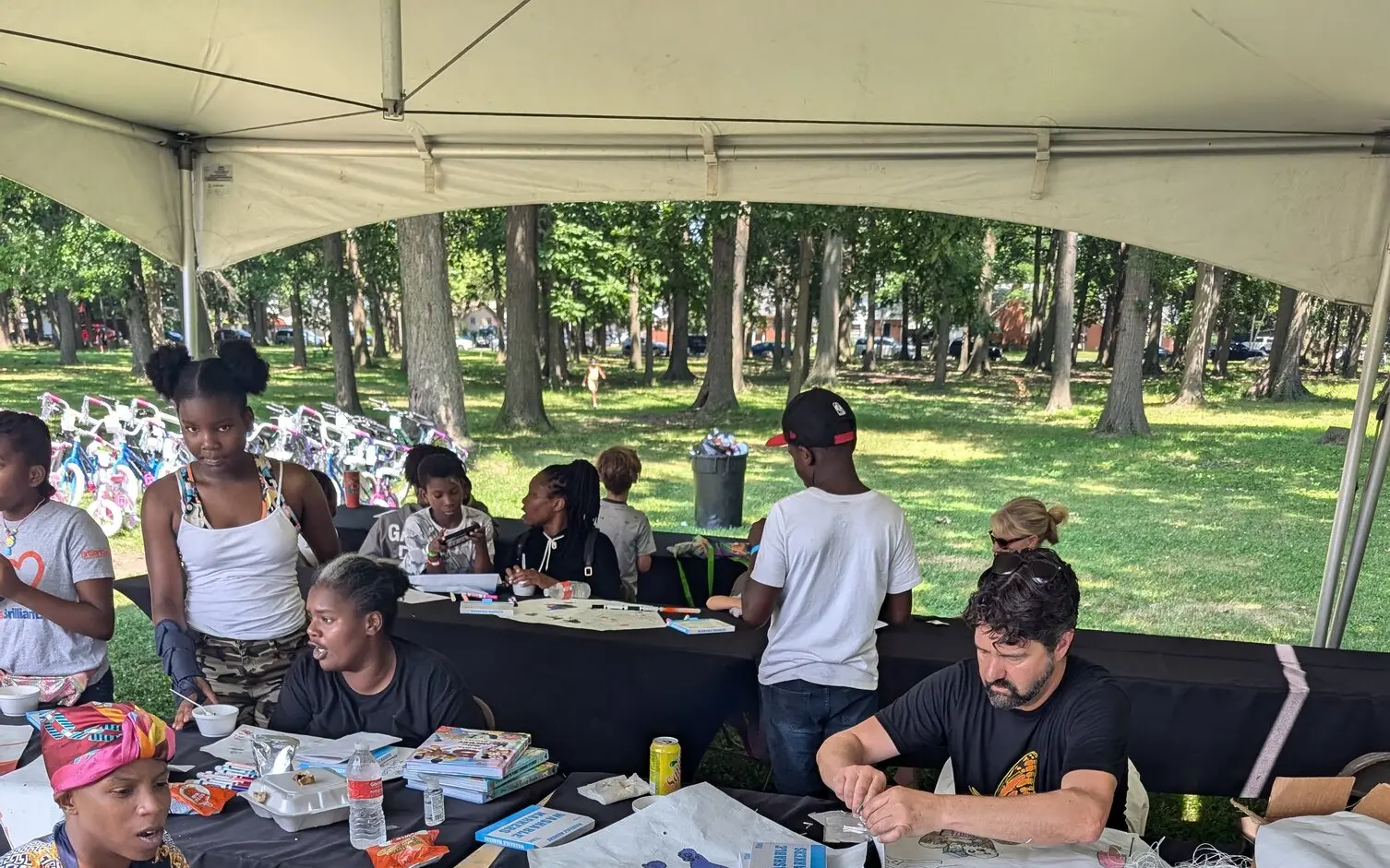 Families and volunteers at an outdoor L.I.V.E. Outreach community event with arts and crafts activities under a tent