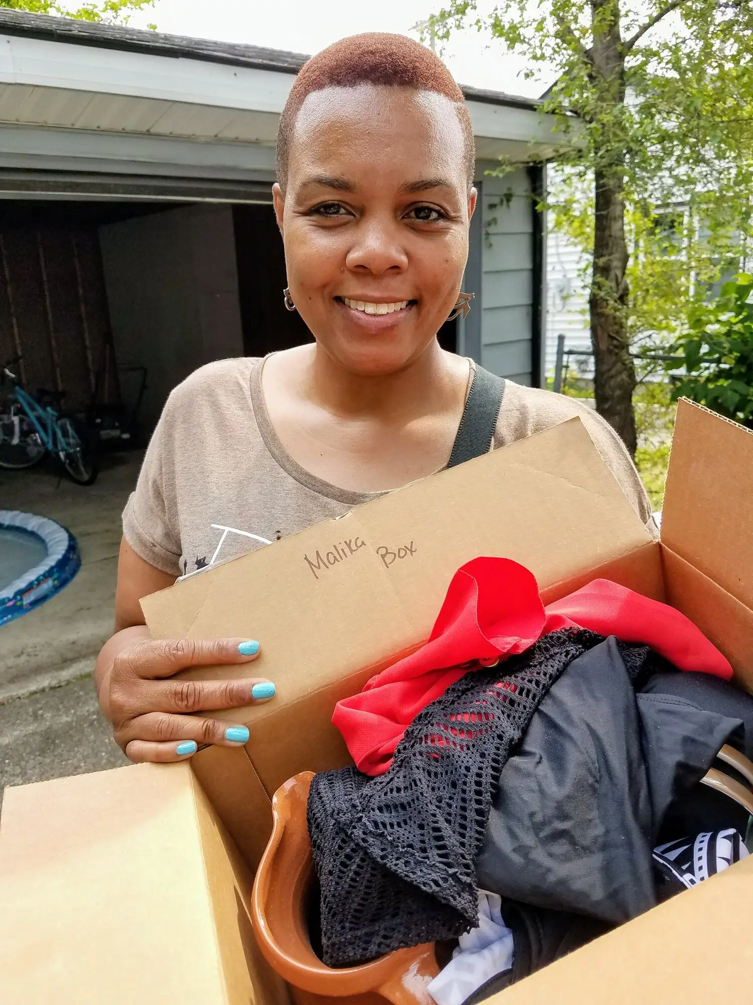 A woman holding a box of donated clothing ready for distribution